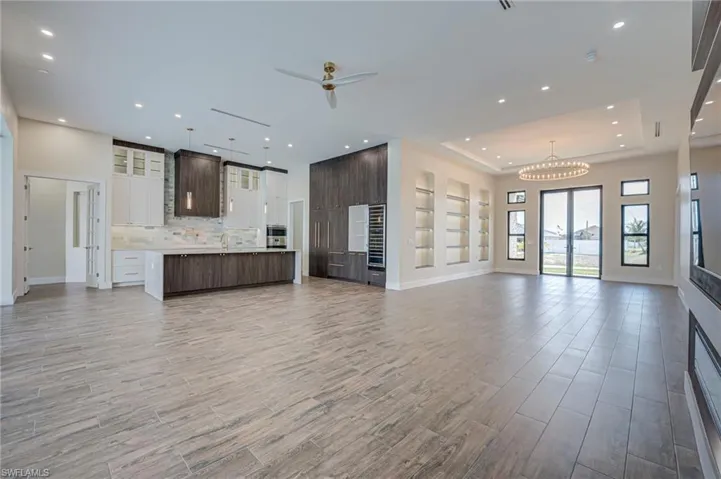 Unfurnished living room with a ceiling fan, light wood-style flooring, a chandelier, and wine cooler