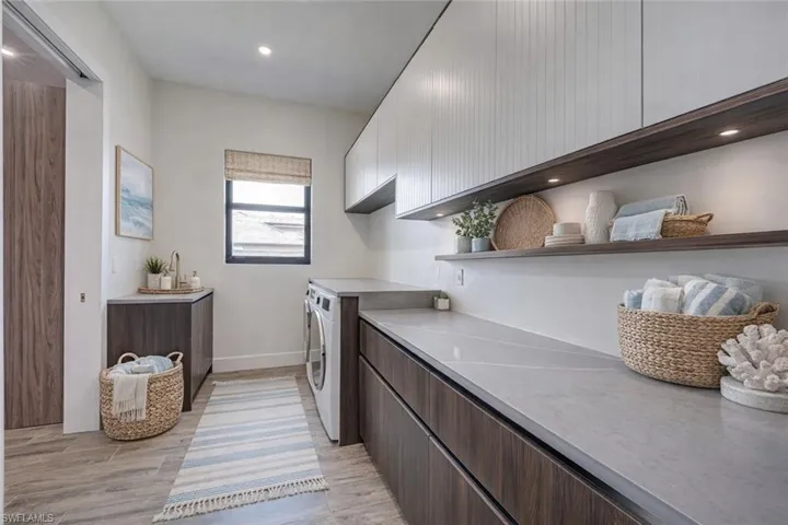 Laundry room with light wood-type flooring, cabinet space, recessed lighting, and washer and dryer
