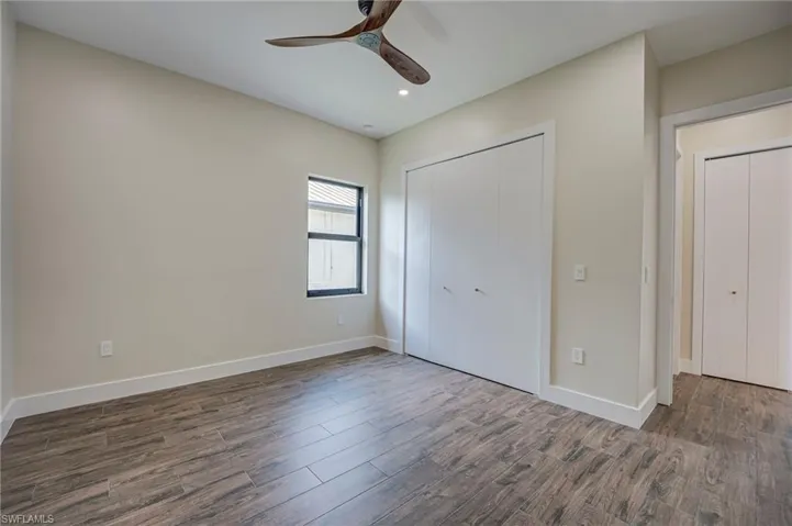 Unfurnished bedroom featuring dark wood-type flooring, a closet, ceiling fan, and recessed lighting