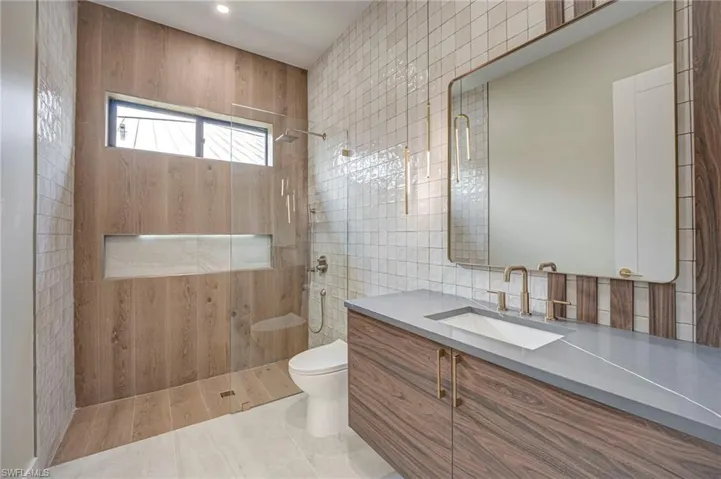 Full bath featuring vanity, walk in shower, tile walls, and light tile patterned floors