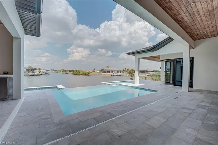 Combined pool / hot tub with a patio area and a water view