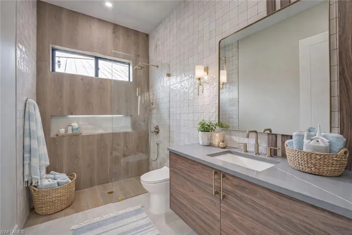 Full bath featuring vanity, a walk in shower, and tile walls