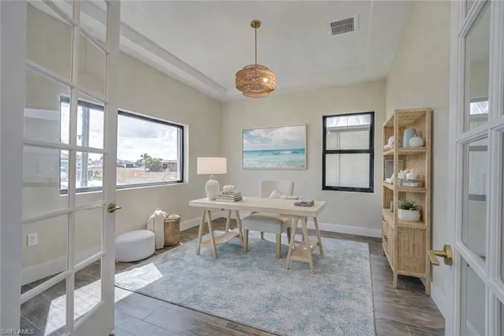 Office area with a raised ceiling and wood finished floors