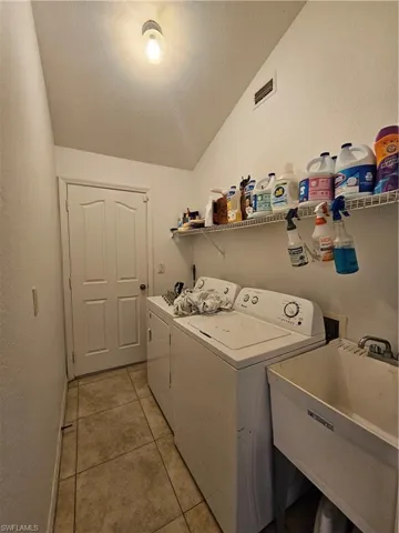 Washroom featuring independent washer and dryer, light tile patterned floors, and a textured ceiling