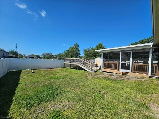 View of yard featuring a sunroom and a wooden deck
