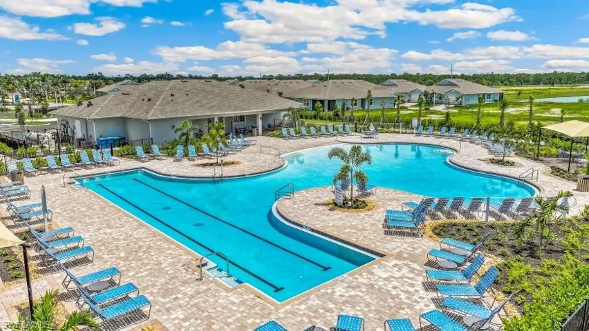 Expansive outdoor pool area featuring a large freeform pool, a rectangular lap pool, and a surrounding paved deck