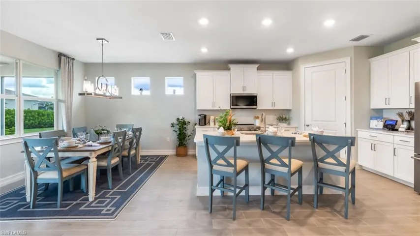 Open-concept kitchen and dining area featuring white cabinetry, recessed lighting, a kitchen island with seating, and wood-finish flooring