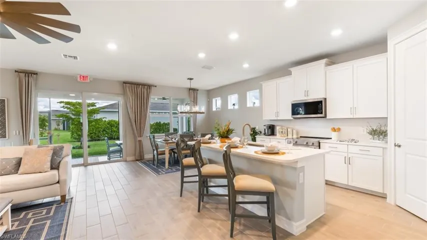 Open-concept layout with wood-finish flooring, white cabinetry, and stainless steel appliances