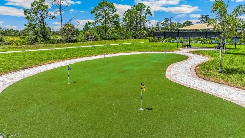 Putting green with multiple flag positions, bordered by a paver pathway