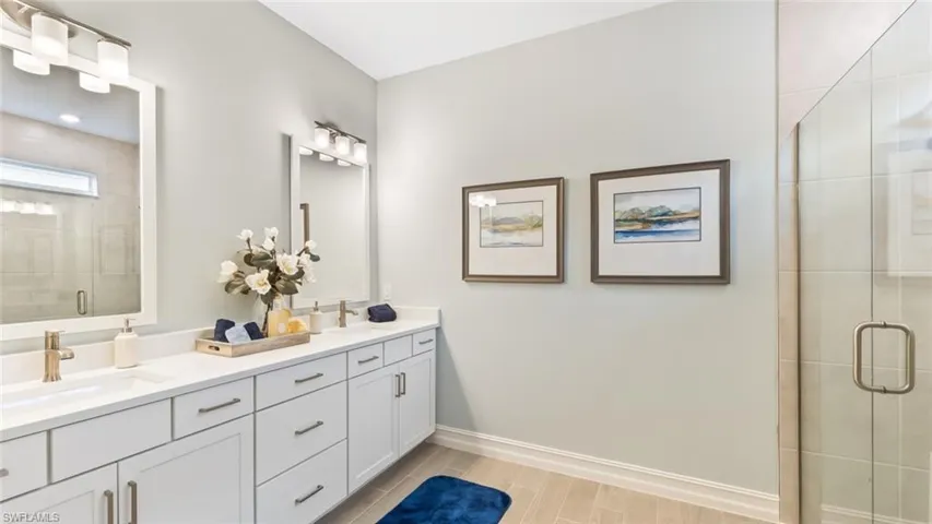 Dual vanity with undermount sinks, white cabinetry, a spacious countertop, and framed mirrors