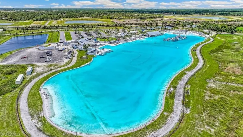 Expansive artificial lagoon with bright blue water, surrounded by green grass and a paved pathway