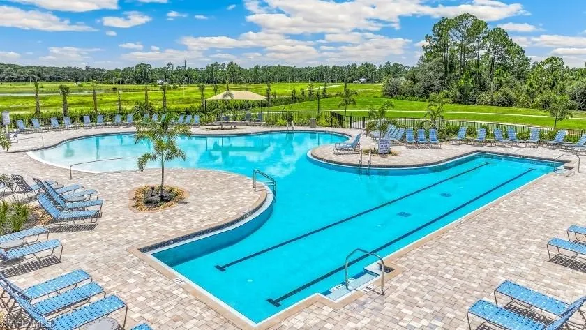 Expansive multi-pool aquatic area featuring a lap lane, surrounding paver decking, and mature landscaping