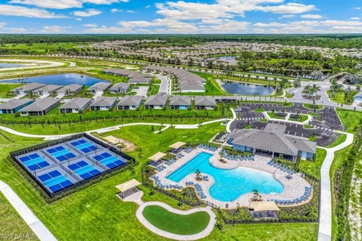 Community clubhouse with an expansive pool deck, large swimming pool, six pickleball courts, and a putting green, all surrounded by green spaces and residential properties