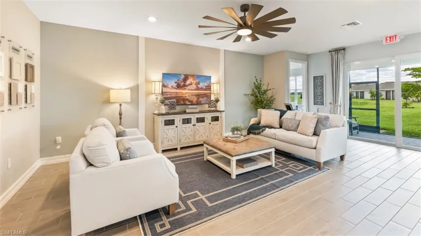 Spacious living area featuring wood-finish flooring, a modern ceiling fan, recessed lighting, and sliding glass doors opening to the exterior