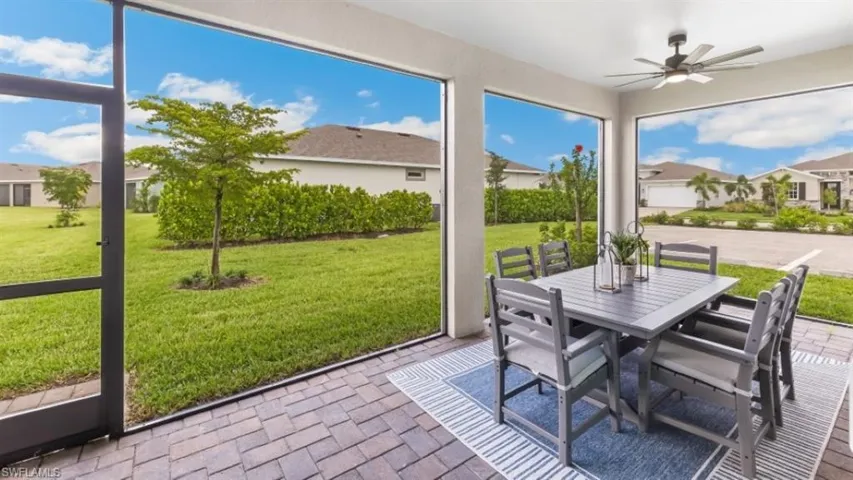 Screened patio with a ceiling fan, paver flooring, and a manicured lawn