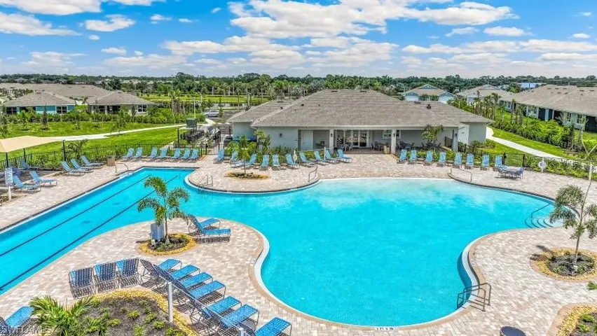 Expansive resort-style pool with a dedicated lap lane, surrounding paver patio, and lush landscaping