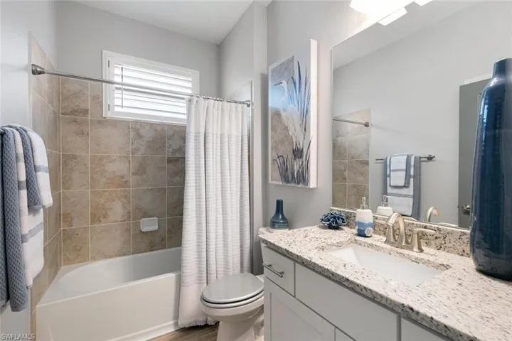 Full bathroom featuring shower / bathtub combination with curtain, hardwood / wood-style floors, vanity, and toilet