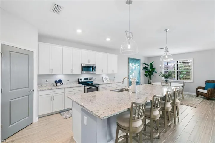 Kitchen with white cabinets, sink, a center island with sink, stainless steel appliances, and light hardwood / wood-style floors