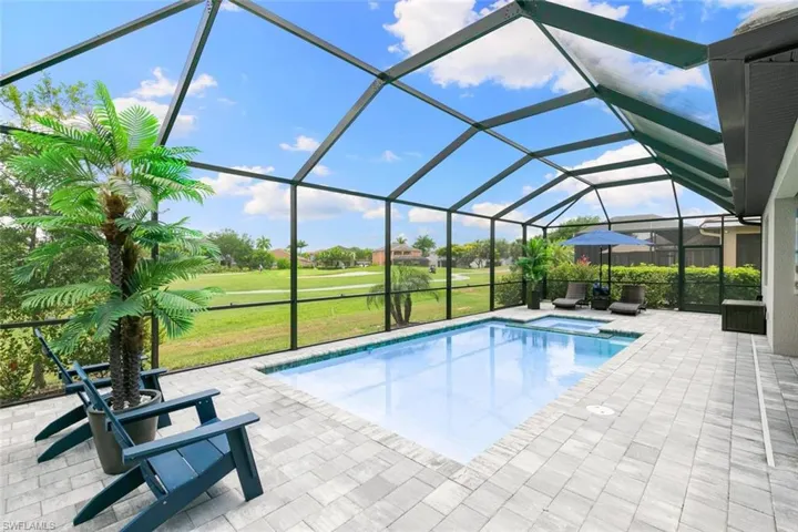 View of pool featuring a lawn, a hot tub, glass enclosure, and a patio area