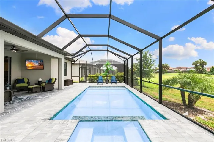 View of pool featuring a patio, glass enclosure, and ceiling fan