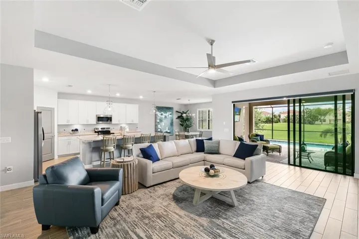 Living room with a raised ceiling, light hardwood / wood-style floors, and ceiling fan