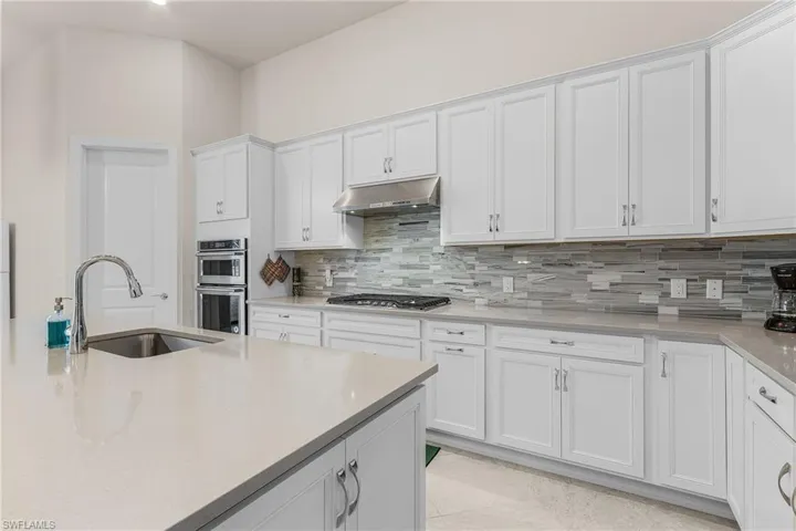 Kitchen featuring white cabinetry, appliances with stainless steel finishes, tasteful backsplash, and sink