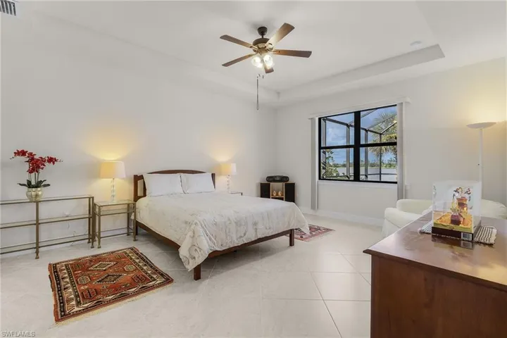 Bedroom with a tray ceiling, ceiling fan, and light tile patterned floors