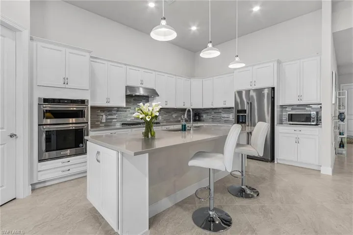 Kitchen with appliances with stainless steel finishes, a kitchen breakfast bar, sink, white cabinetry, and an island with sink