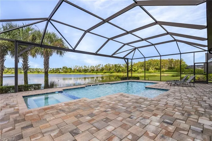 View of swimming pool featuring a lanai, a water view, an in ground hot tub, and a patio area