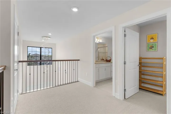 Hall featuring light carpet, a notable chandelier, and sink