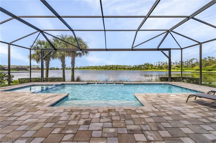View of swimming pool with a water view, glass enclosure, and a patio area