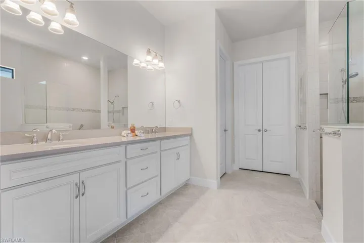 Bathroom with vanity, tile patterned floors, and tiled shower