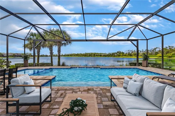 View of pool featuring a lanai, a water view, a patio, and an outdoor hangout area