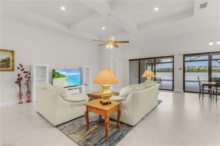 Tiled living room with a high ceiling, beamed ceiling, ceiling fan, and coffered ceiling