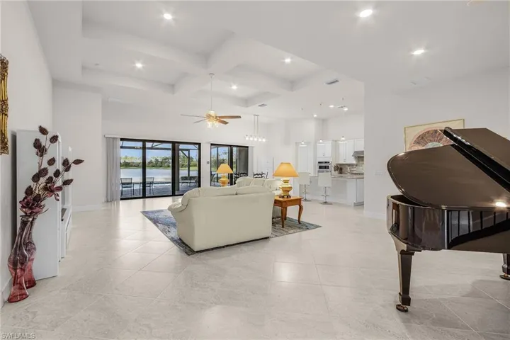 Living room featuring a high ceiling, beam ceiling, ceiling fan, and coffered ceiling