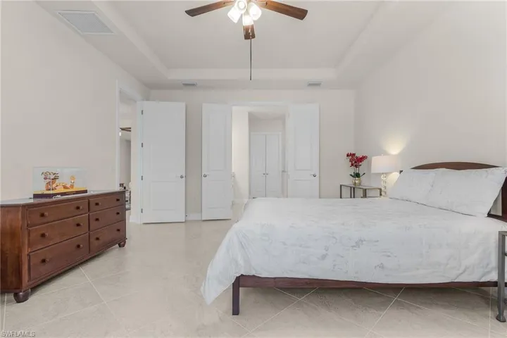 Tiled bedroom with a tray ceiling and ceiling fan