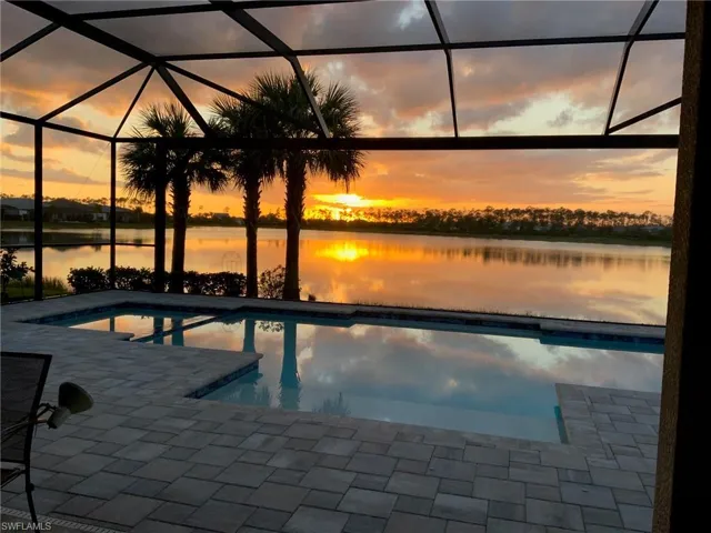 Pool at dusk with a water view, a patio area, and a lanai