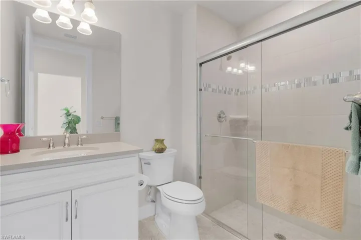 Bathroom featuring tile patterned floors, an enclosed shower, vanity, and toilet