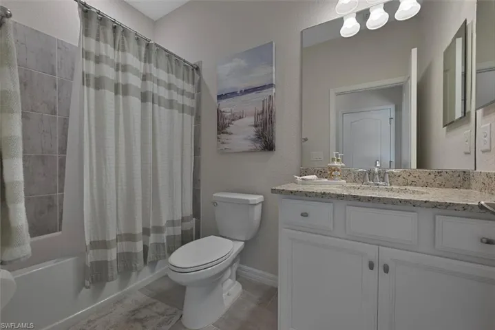 Full bathroom featuring shower / tub combo with curtain, vanity, and tile patterned flooring