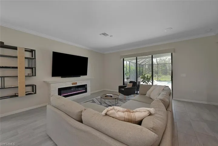 Living room with ornamental molding, a glass covered fireplace, and a sunroom