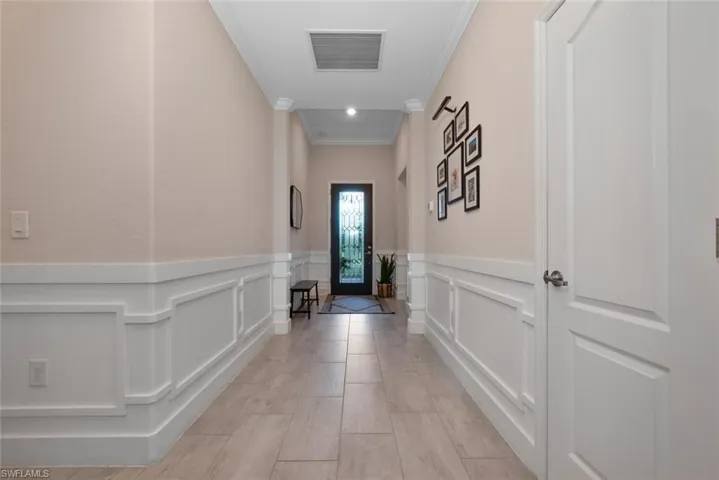 Corridor featuring ornamental molding, wainscoting, and a decorative wall