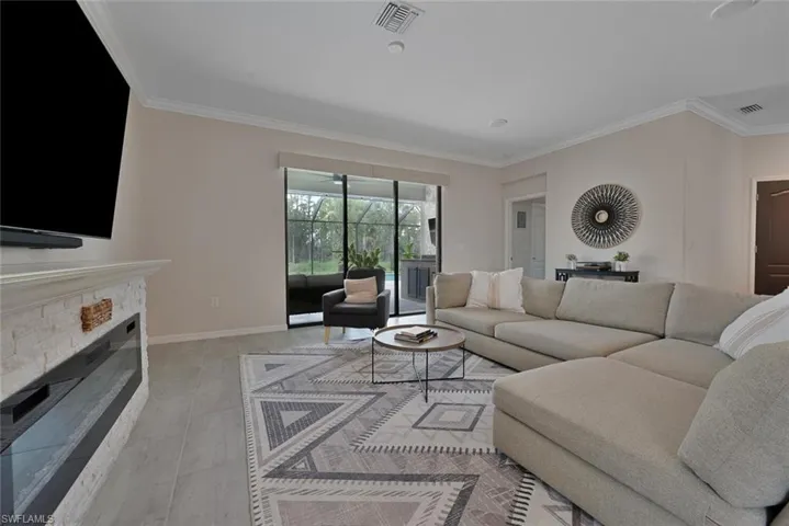 Living area with ornamental molding and a stone fireplace