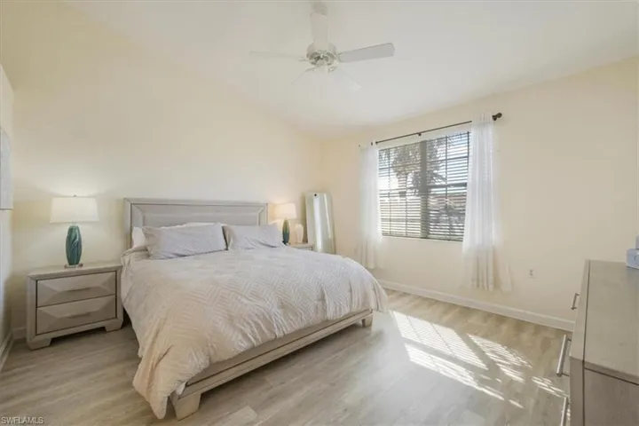 Bedroom with vaulted ceiling, light wood-type flooring, and a ceiling fan