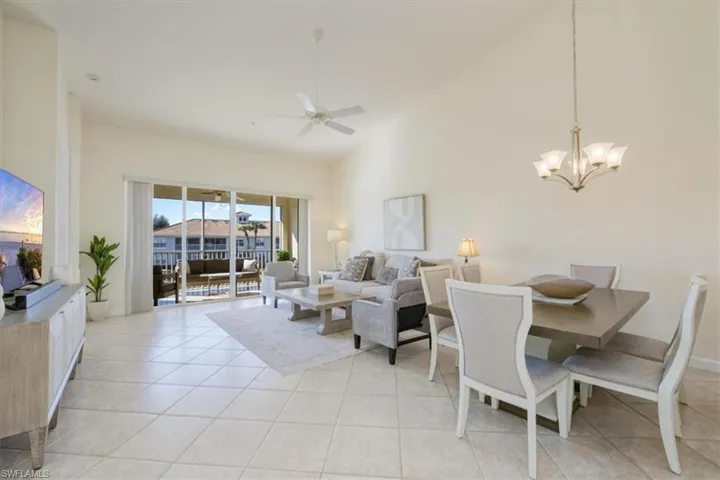 Living room with high vaulted ceiling, a chandelier, a ceiling fan, and light tile patterned floors