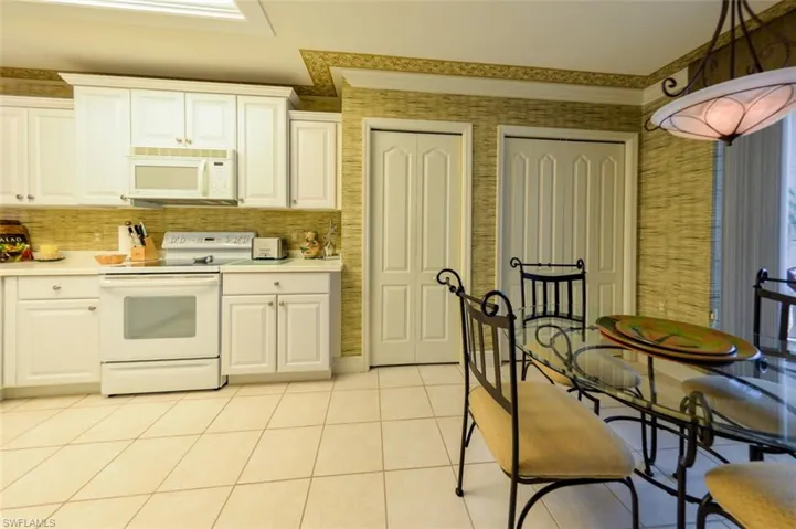 Kitchen with white cabinetry, pendant lighting, white appliances, and light tile patterned floors