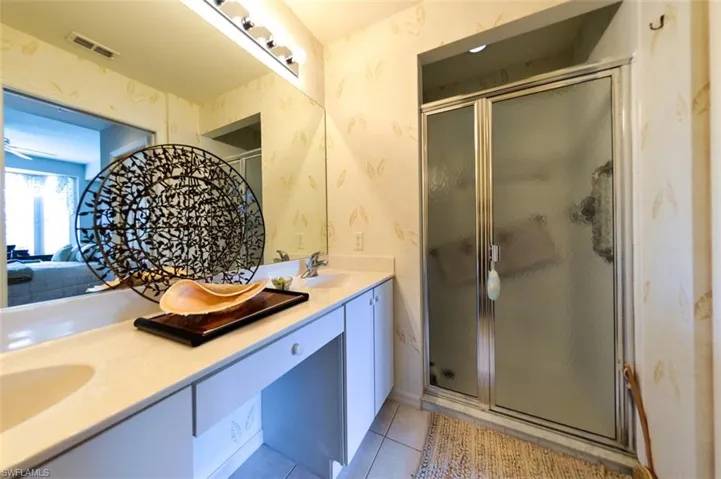 Bathroom featuring vanity, walk in shower, and tile patterned flooring