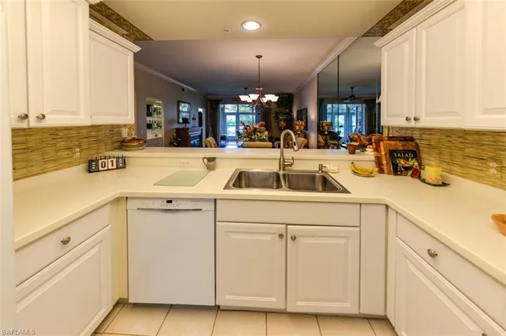 Kitchen featuring kitchen peninsula, dishwasher, light tile patterned flooring, a notable chandelier, and sink