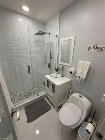 Full bath featuring a stall shower, vanity, light marble finish flooring, and recessed lighting