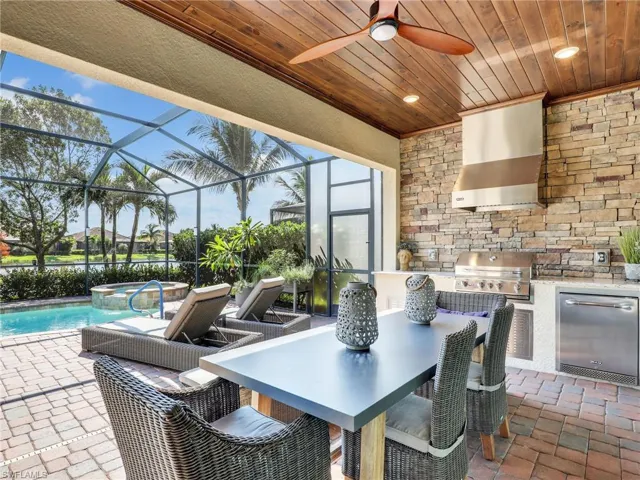 View of patio / terrace featuring a grill, an outdoor kitchen, a pool with hot tub, a lanai, and ceiling fan