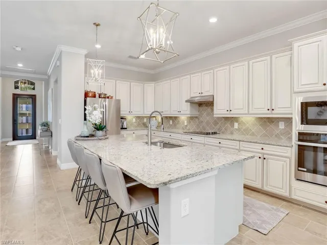 Kitchen with light stone countertops, sink, appliances with stainless steel finishes, and white cabinetry